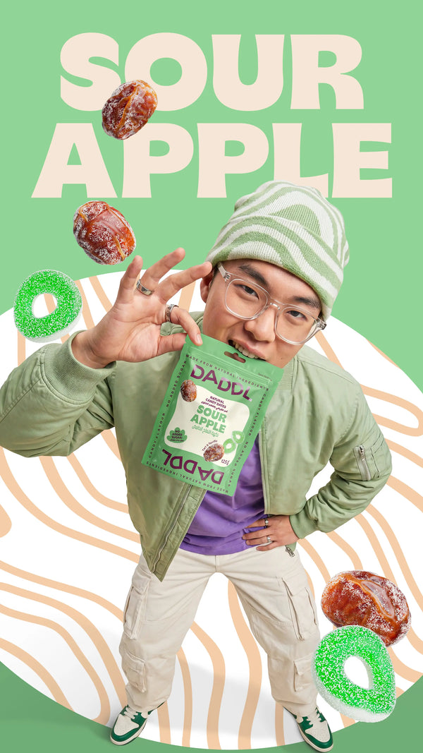 Young man in green streetwear holding a DADDL Sour Apple candy dates pouch against a pastel green background with large “SOUR APPLE” text, floating candy dates, and green sour candy rings in a playful Coachella-inspired campaign design.