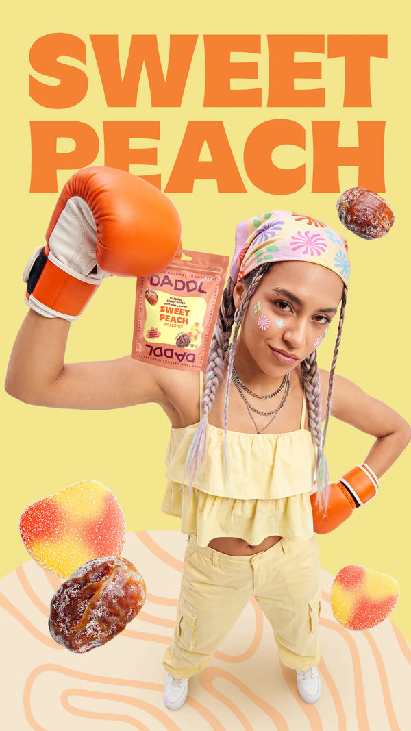 Young woman with braided hair wearing orange boxing gloves and holding a DADDL Sweet Peach candy dates pouch against a yellow background with large “SWEET PEACH” text, floating coated dates, and peach gummy candies.