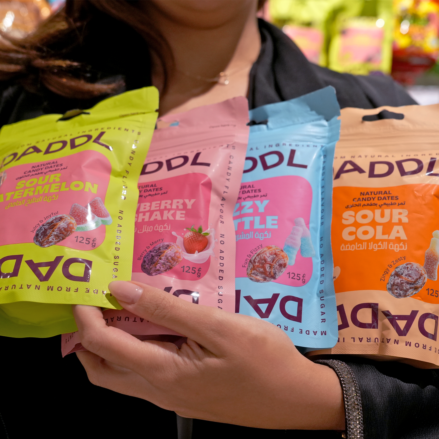 Four DADDL candy packages in different flavors held by a person.