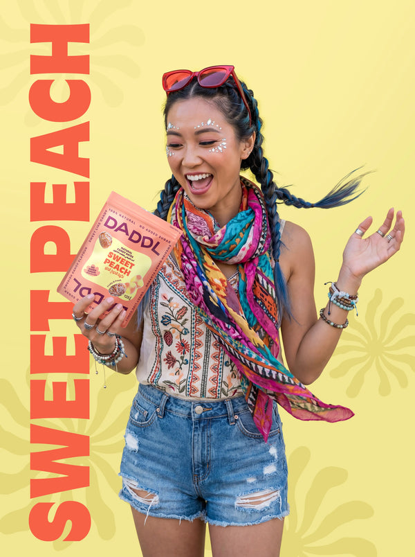 Person holding a box of Daddl Sweet Peach candy against a yellow background