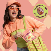 Person holding a bag of Daddl snacks with a pink and green color scheme on a pink background.